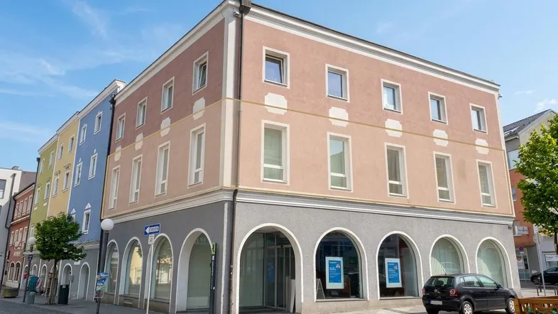 Mehrstöckiges Gebäude mit Geschäften im Erdgeschoss und Büros oder Wohnungen darüber, an einer städtischen Straße gelegen.