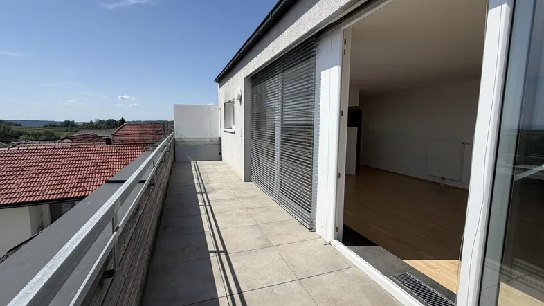Große Dachterrasse mit Fliesenboden, weitem Blick über die Dächer und Zugang zum Wohnbereich.