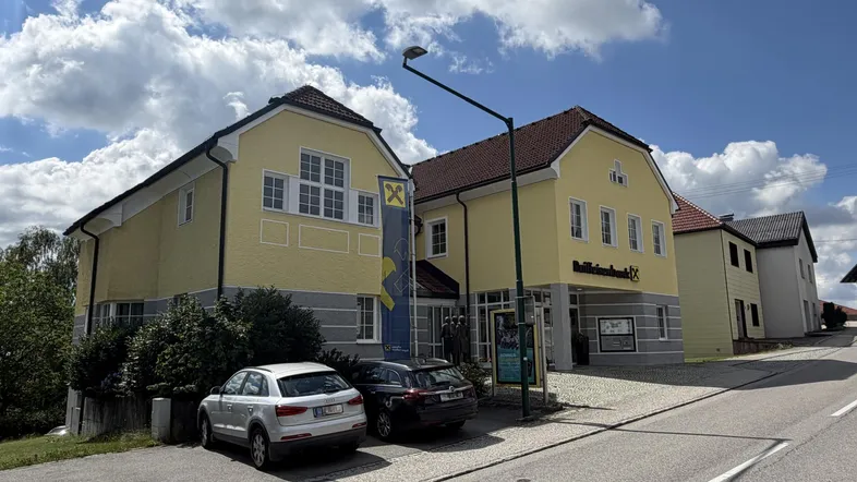Ansicht eines gepflegten Gebäudes mit gelber Fassade und traditioneller Architektur in einer ländlichen Umgebung.