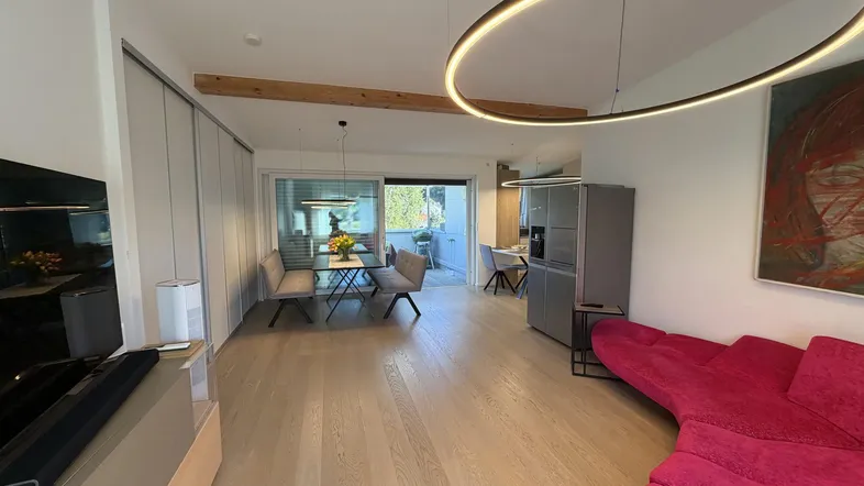 Heller offener Wohn- und Essbereich mit Holzboden, moderner Beleuchtung und Zugang zur Terrasse.