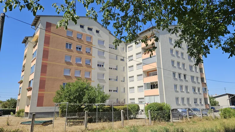 Mehrstöckiges Wohngebäude mit farbigen Fassadenabschnitten und vielen Fenstern unter blauem Himmel.