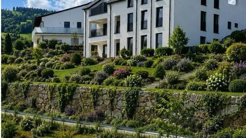 Modernes Gebäude mit Photovoltaikanlage und einem aufwendig gestalteten, terrassierten Gartenbereich.