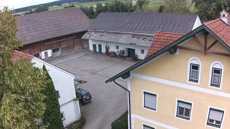 Luftaufnahme eines ländlichen Anwesens mit mehreren Gebäuden, einem großen Hof und grüner Umgebung.