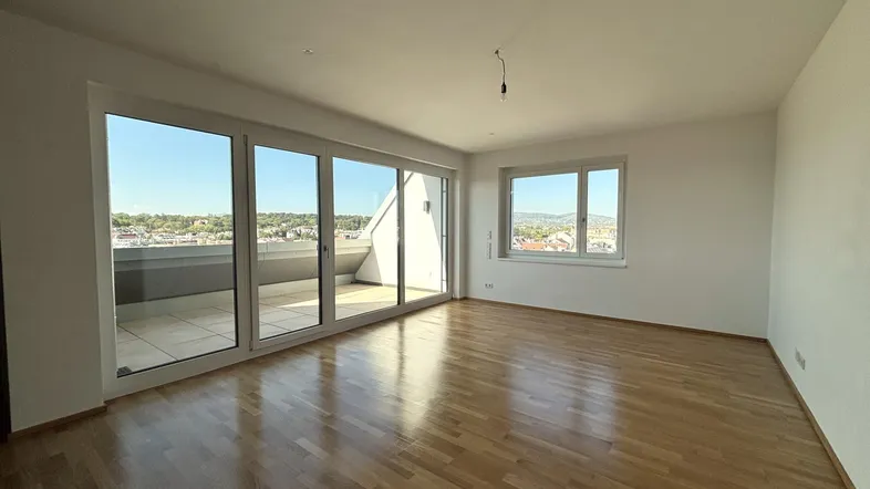 Helles Wohnzimmer mit Parkettboden, großen Fenstern und Zugang zu einer Terrasse mit Stadtblick.