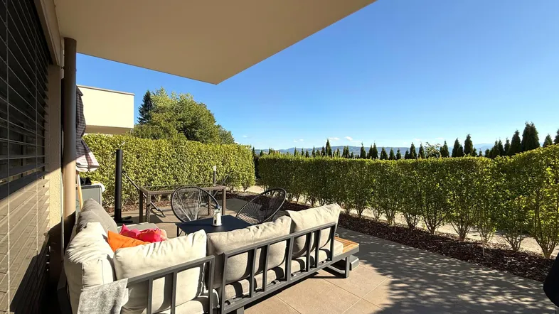 Große, sonnige Terrasse mit bequemen Loungemöbeln und weitem Blick in die Landschaft.