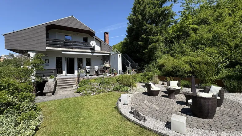 Gepflegter Garten mit großer Terrasse, gemütlicher Sitzgruppe und Zugang zum Haus.