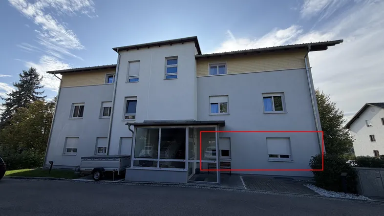 Außenansicht eines Mehrfamilienhauses mit heller Fassade und verglastem Eingangsbereich.