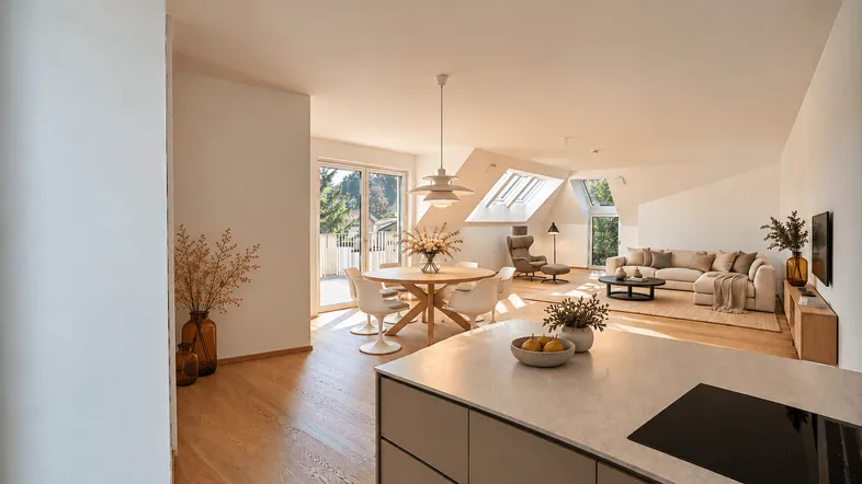 Helles, offenes Wohnzimmer mit Essbereich, Küche und Zugang zum Balkon.