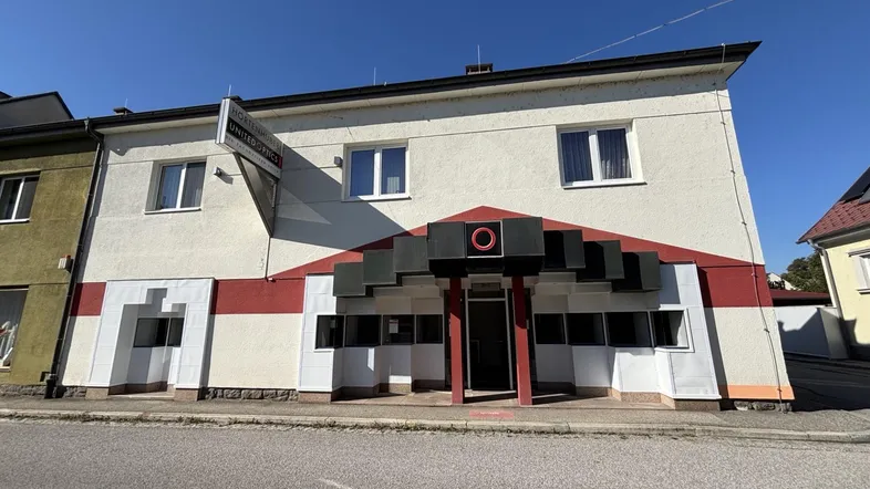 Gebäudeansicht eines zweistöckigen Geschäftsgebäudes mit weißer Fassade und markantem Eingangsbereich.