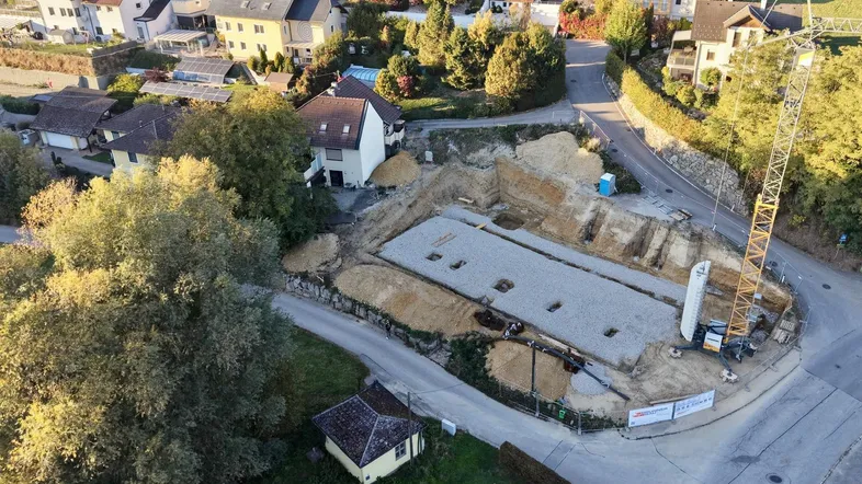 Luftaufnahme einer Baustelle mit Kran und umliegenden Wohnhäusern in ländlicher Umgebung.