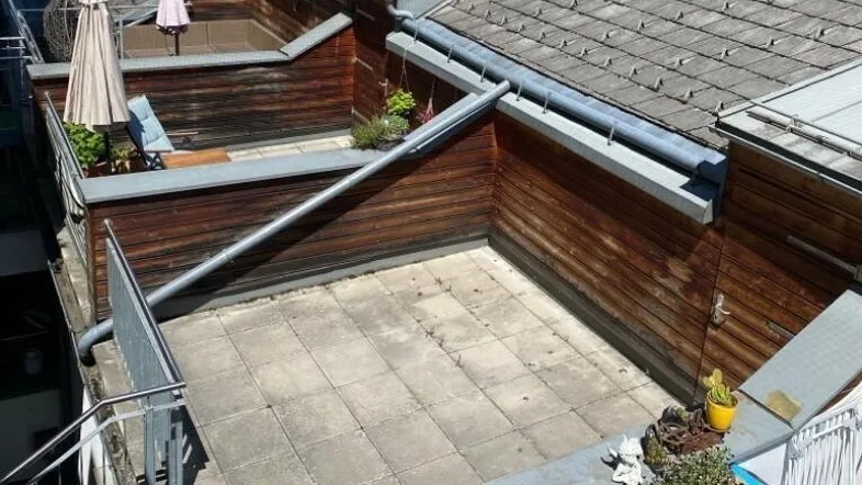 Geräumige Dachterrasse mit Fliesenboden und Holzverkleidung, ideal für Entspannung im Freien.