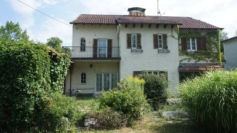 Historisches Haus mit charmantem Garten, Balkon und bewachsenen Fassaden.
