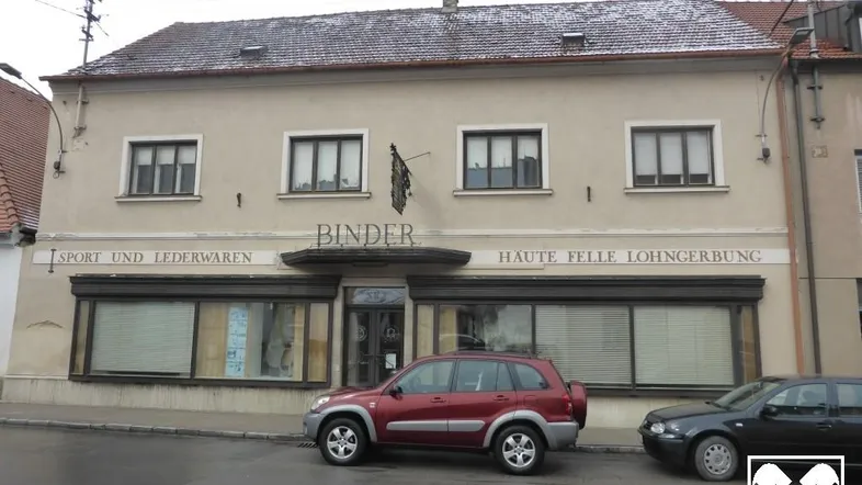 Fassade eines älteren Gebäudes mit Ladenfront und Fenstern im Obergeschoss, das eine Renovierung benötigt.