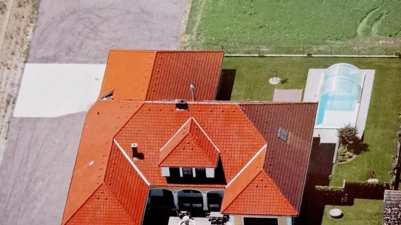 Luftaufnahme des Anwesens mit Wohnhaus, Pool und angrenzendem Feld.