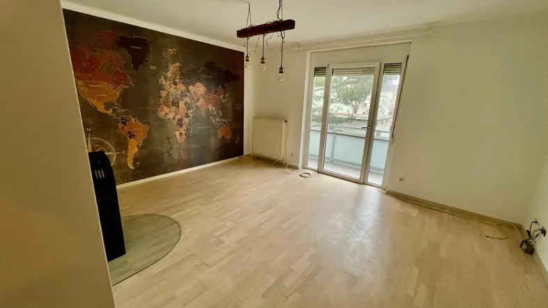 Helles Wohnzimmer mit Holzboden, Weltkarten-Tapete und Zugang zum Balkon.