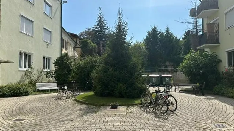 Innenhof mit gepflastertem Bereich, Bäumen und Fahrradstellplätzen zwischen Wohngebäuden.
