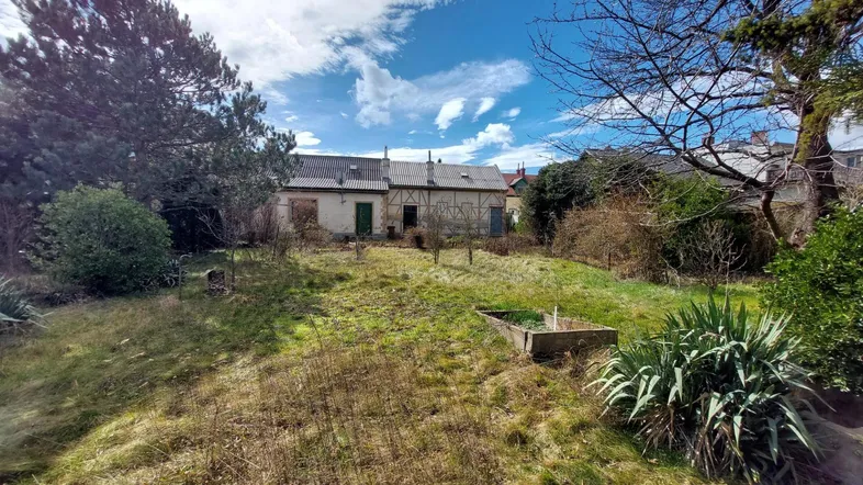 Hanglage im Garten mit Blick auf das sanierungsbedürftige Gebäude und alte Bäume.