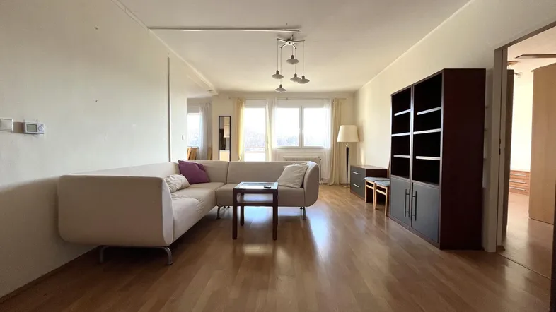 Geräumiges Wohnzimmer mit hellem Parkettboden, beigem Sofa und großen Fenstern für viel Tageslicht.