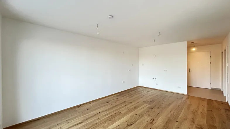 Geräumiges, unmöbliertes Zimmer mit hellem Parkettboden und weiß gestrichenen Wänden, bereit zum Einzug.