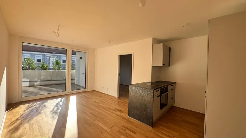 Heller Wohn- und Essbereich mit Parkettboden, moderner Küchenzeile und Zugang zur Terrasse.