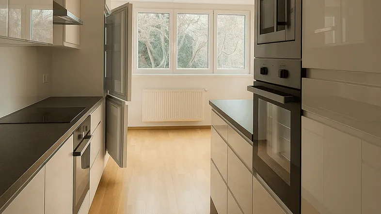 Lange, helle Küche mit Einbaugeräten, Fenster und Blick ins Freie.