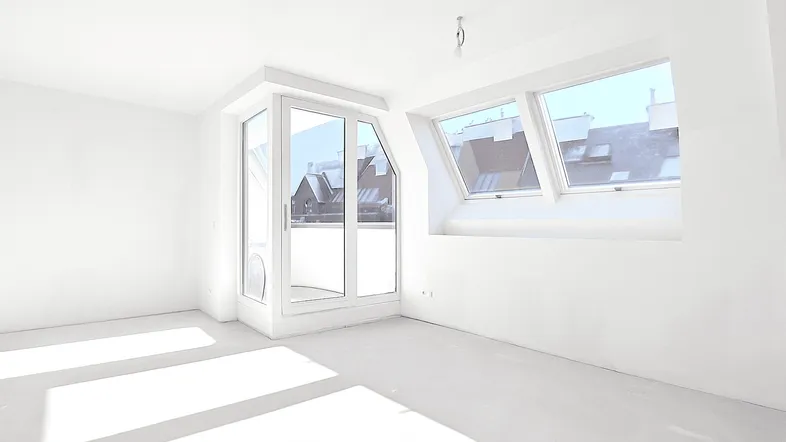 Lichtdurchfluteter Raum im Dachgeschoss mit Dachfenstern und Zugang zu einem Balkon.