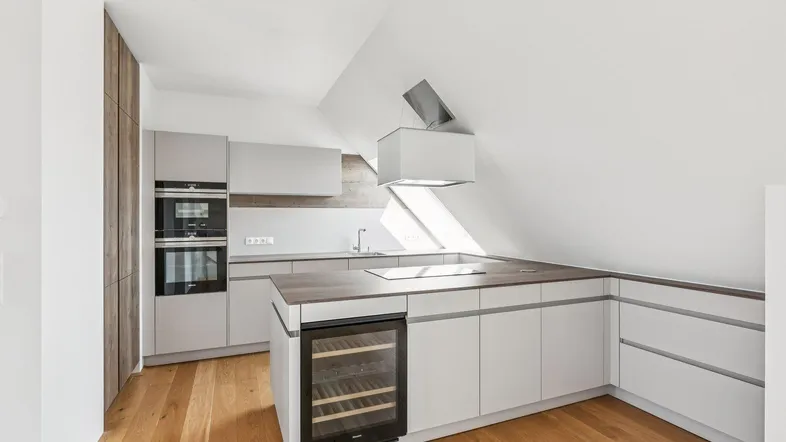 Moderne Küche im Dachgeschoss mit Holzboden, integrierten Geräten und Weinkühlschrank.
