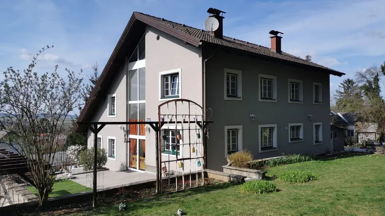 Großzügiges Einfamilienhaus mit Satteldach, großen Fenstern und gepflegtem Gartenbereich.