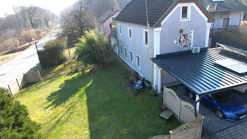 Luftaufnahme des Hauses mit Garten, Carport und Solaranlage an einem sonnigen Tag.