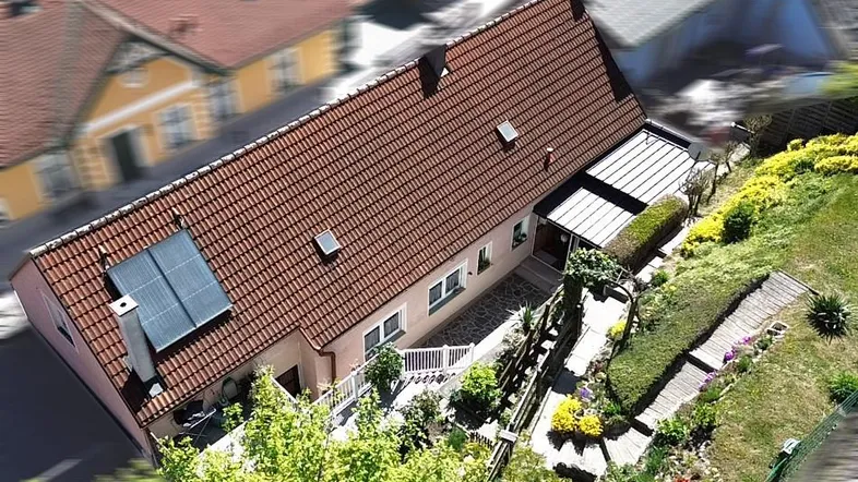Luftaufnahme des Hauses mit rotem Ziegeldach, Solarpaneelen und einem gepflegten Gartenbereich.