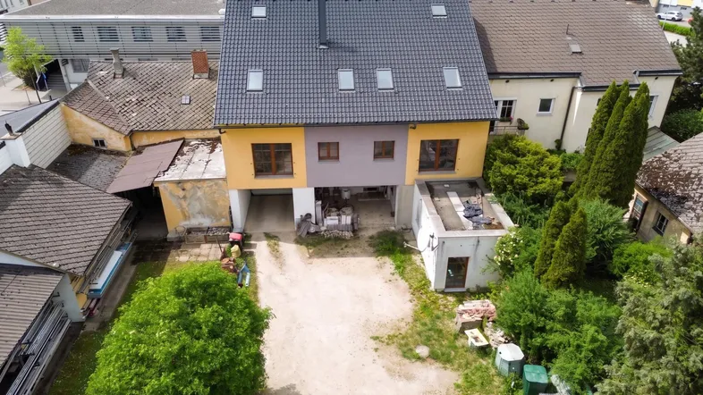 Luftaufnahme eines Wohnhauses mit Garten und umliegenden Gebäuden in städtischer Umgebung.
