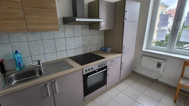 Funktionale Küche mit Einbauschränken, Kochfeld, Backofen und Fenster mit Blick ins Grüne.