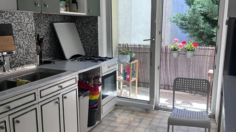 Helle Küche mit hellgrauen Schränken, Mosaikfliesen und Zugang zum Balkon.