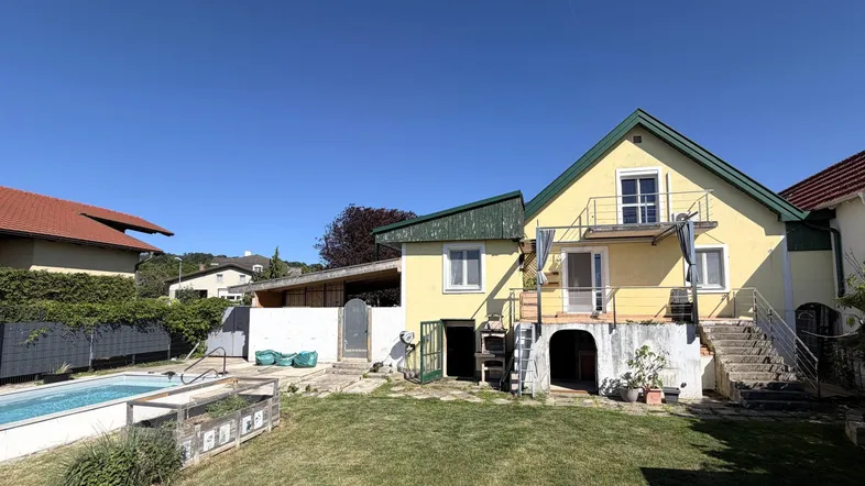 Großzügiger Gartenbereich mit Swimmingpool und Rasenfläche hinter dem gelben Haus.