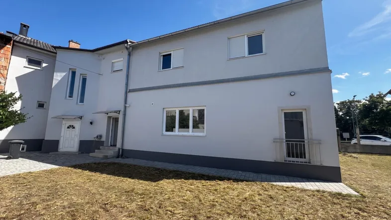 Seitenansicht des Gebäudes mit weißer Fassade, mehreren Fenstern und kleinen französischen Balkonen.