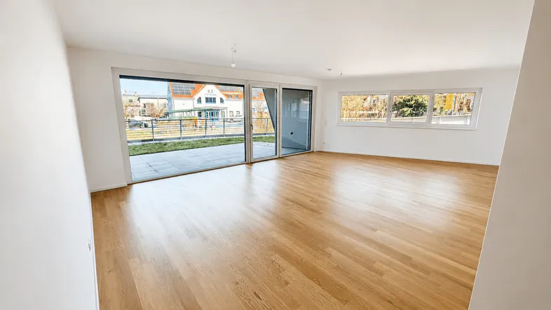 Helles Wohnzimmer mit neuem Parkettboden und großen Schiebetüren zur Terrasse.