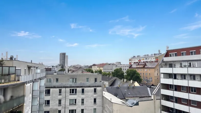 Weitläufiger Blick über die Stadt mit verschiedenen Gebäuden unter blauem Himmel.