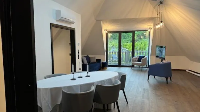 Geräumiger Wohn- und Essbereich im Dachgeschoss mit Holzboden und Zugang zum Balkon.