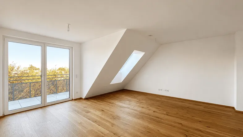 Heller Dachgeschossraum mit Holzboden, Schrägdecke, Dachfenster und Zugang zum Balkon.