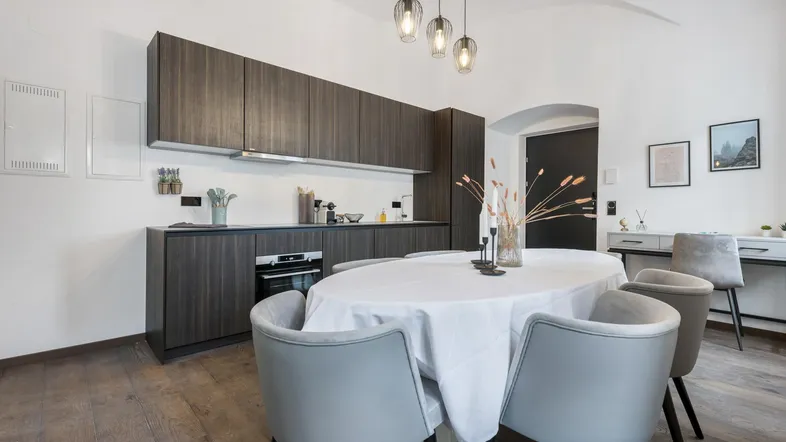 Moderne Küche mit dunklen Holzfronten und Essbereich unter einer Gewölbedecke.