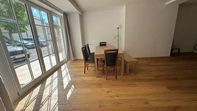 Essbereich mit Holztisch und Stühlen, direkt an großen Fenstern mit viel Tageslicht.