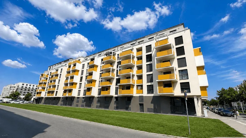 Modernes Mehrfamilienhaus mit farbigen Balkonen und klarer Architektur unter blauem Himmel.