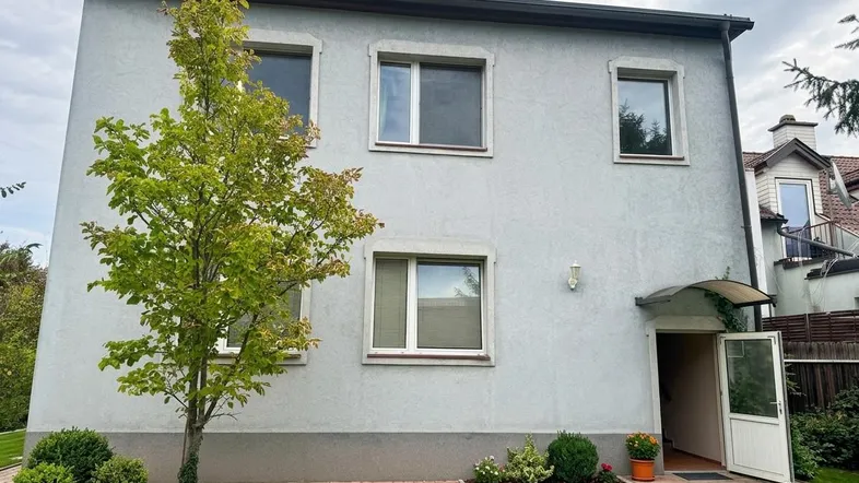 Vorderansicht des Hauses mit hellgrauer Fassade, Fenstern und Eingangsbereich.