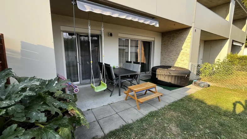 Gemütliche Terrasse mit Gartenmöbeln, Schaukel und aufblasbarem Whirlpool im Freien.