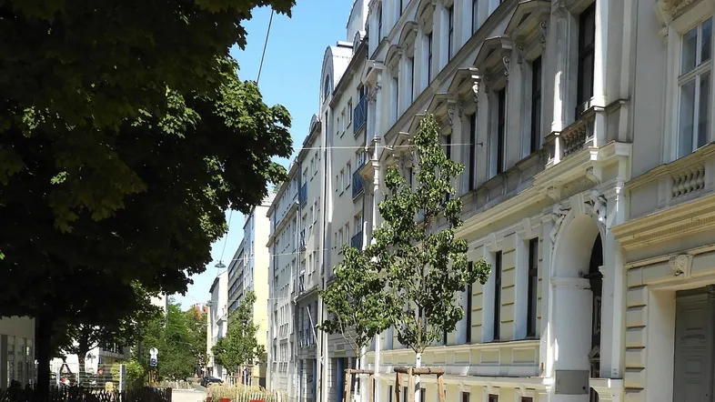 Historische Fassade eines Mehrfamilienhauses an einer von Bäumen gesäumten Straße.