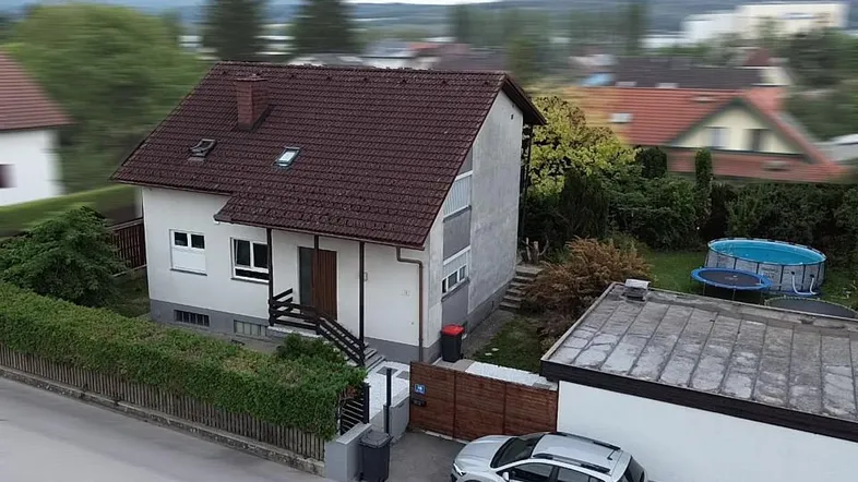 Luftaufnahme eines Einfamilienhauses mit Satteldach, Garten und einem Auto auf dem Stellplatz.