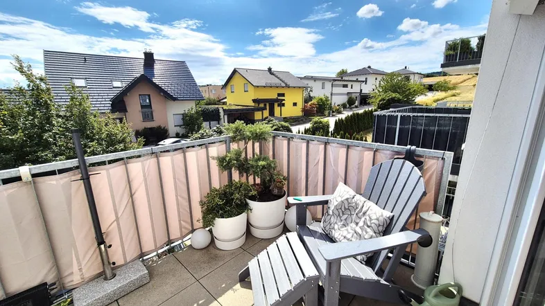Sonniger Balkon mit bequemen Gartenmöbeln und Blick auf die umliegende Nachbarschaft.