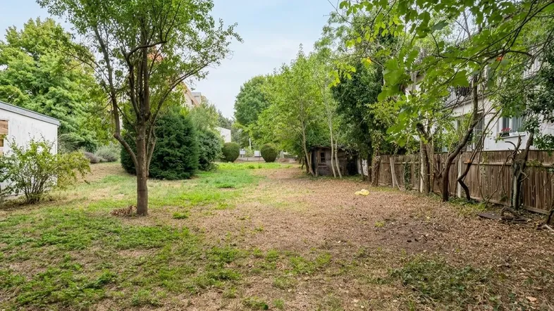 Großes, unbebautes Grundstück mit Bäumen und Sträuchern, umgeben von weiterer Vegetation.
