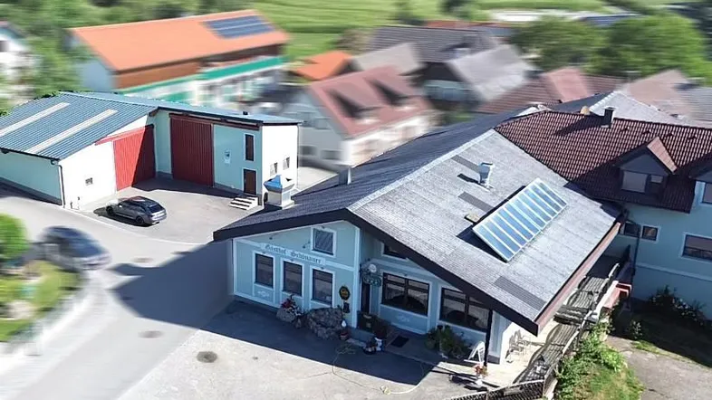 Luftaufnahme eines Gebäudekomplexes mit Solaranlagen auf den Dächern in ländlicher Umgebung.