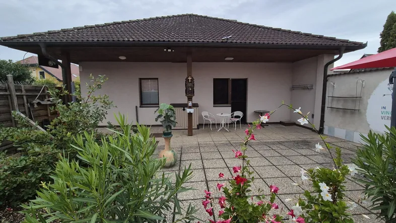 Überdachte Terrasse mit Sitzgelegenheiten und Blick auf den Gartenbereich des Hauses.